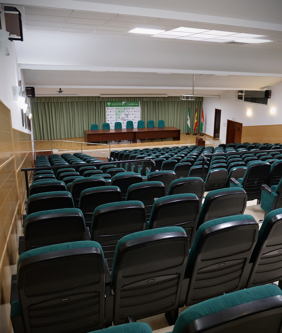 Salón de actos vacío de la Facultad de Ciencias del Deporte visto desde el fondo lateral izquierdo de la sala